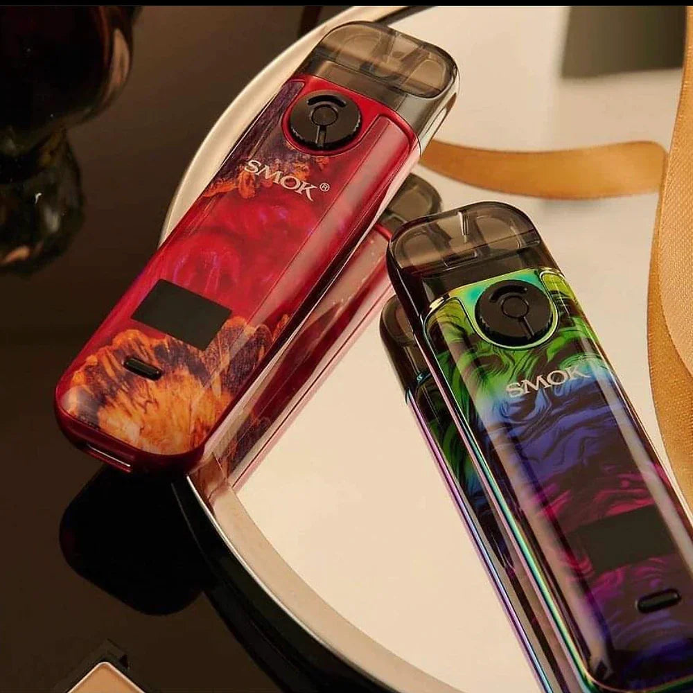 Two SMOK NOVO 4 Pod Kits - 25W in red and rainbow swirl finishes placed on a mirror, highlighting stylish design and compact form.