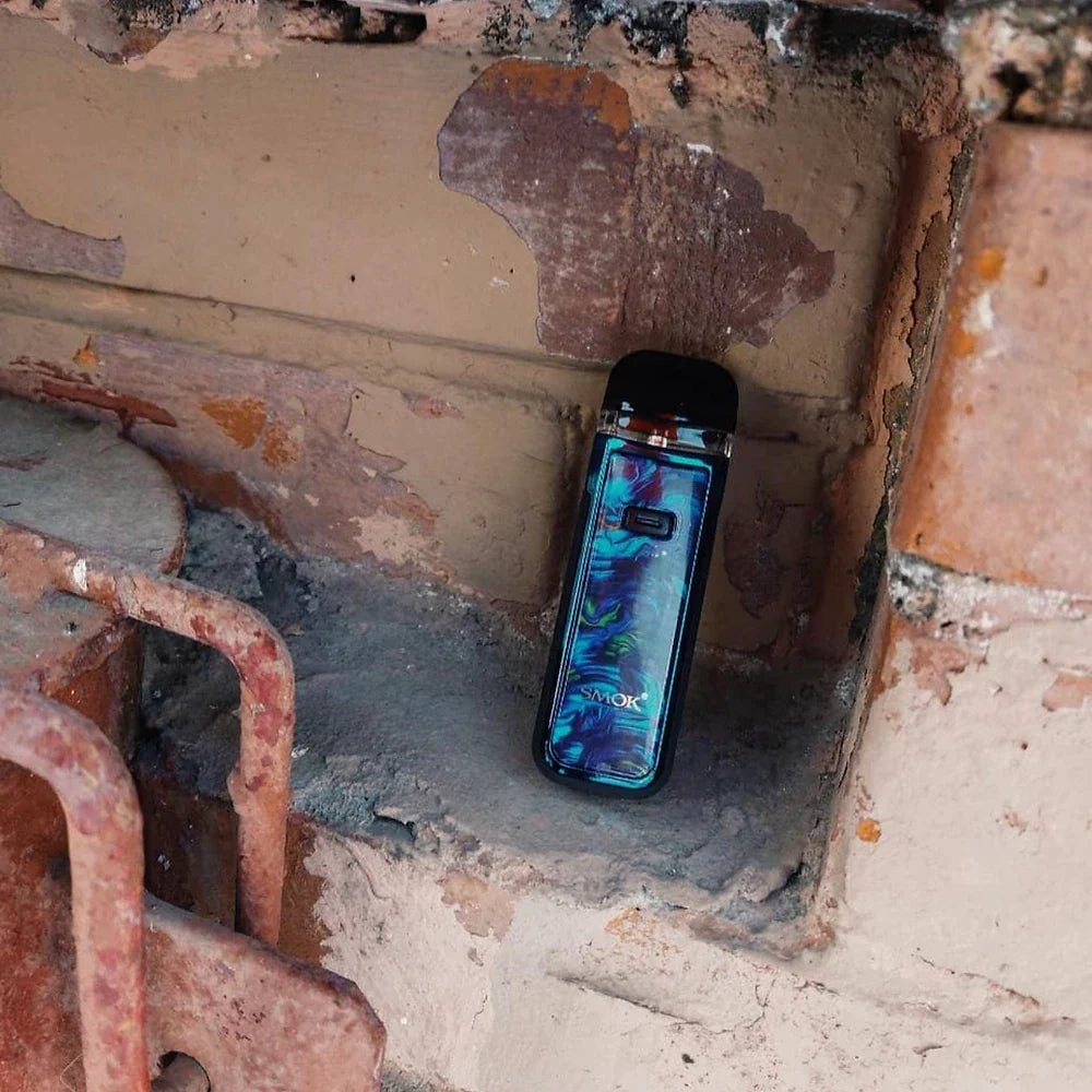 Colorful SMOK NORD X Pod System with 1500mAh battery nestled in rustic wall, showcasing compact and durable vape design.
