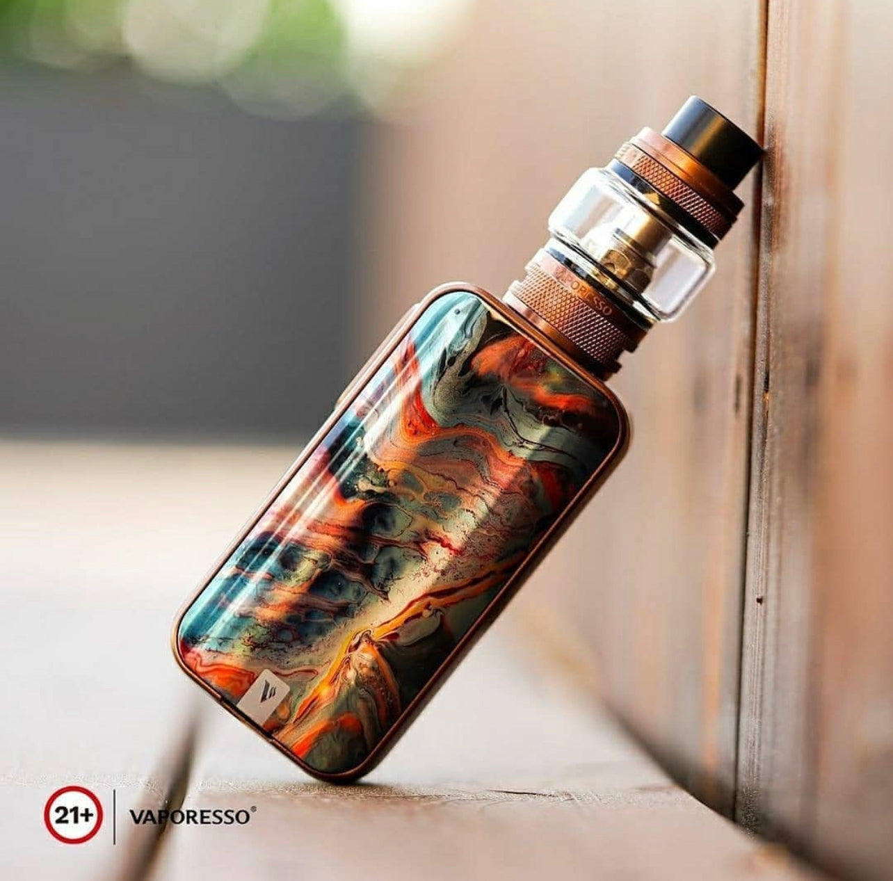 Vaporesso Luxe 2 Starter Kit - 220W Dual Battery Vape with colorful swirl design leaning on wooden surface, highlighting artistic finish.