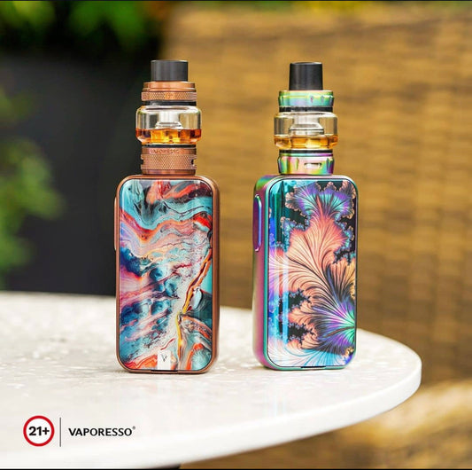Vaporesso Luxe 2 Starter Kit - 220W Dual Battery Vape in vibrant abstract and floral designs, displayed on a white table outdoors.