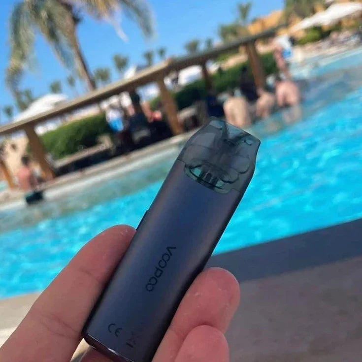 Black VOOPOO V Thru Pro Pod System 25W with 900mAh battery shown poolside, highlighting its portable and sleek design for outdoor vaping.
