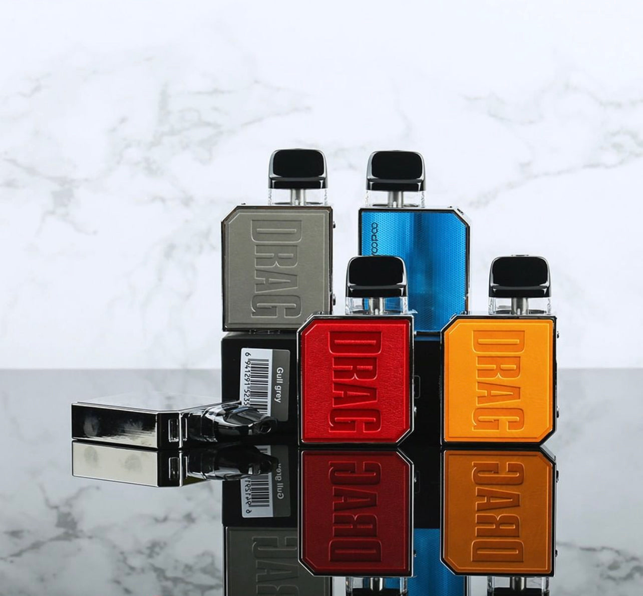 Multiple VOOPOO Drag Nano 2 Pod Systems in various colors including red, blue, and orange, displayed on reflective surface for product variety.